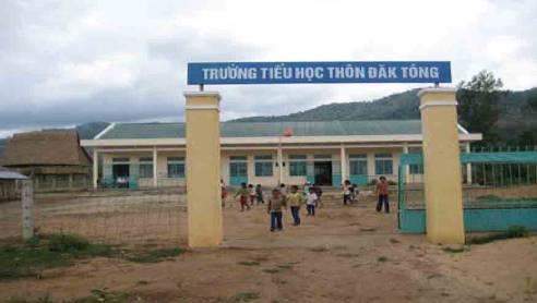 Children play in front of a school building with a sign that reads "Truong Tieu Hoc Tuan Dao Tong" in Vietnamese.